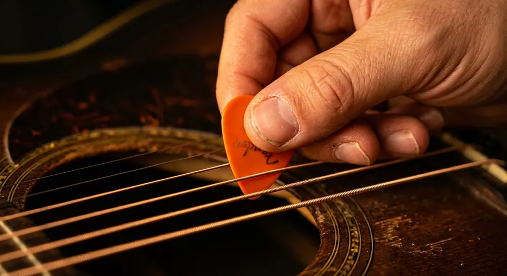 Plectrum dat een gitaarsnaar aanslaat, van dichtbij